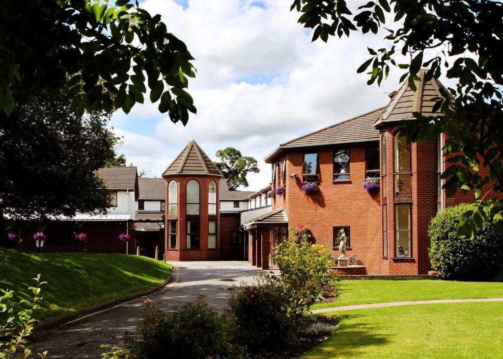 a large brick house with a driveway at Beaufort Park Hotel in Mold