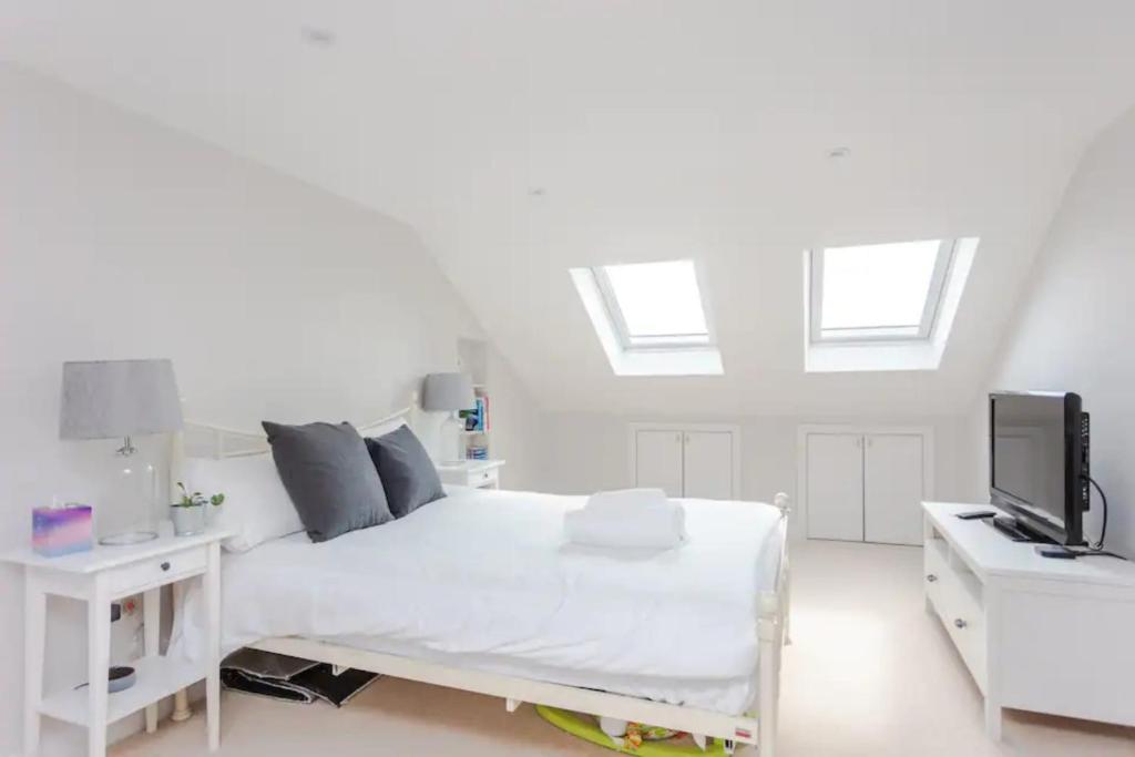 a white bedroom with a white bed and a tv at Modern 3 Bedroom Home in Honor Oak beside Nature Reserve in London