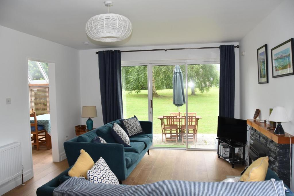 a living room with blue couches and a sliding glass door at Cottage on the grounds of Rathmullan House Hotel in Rathmullan