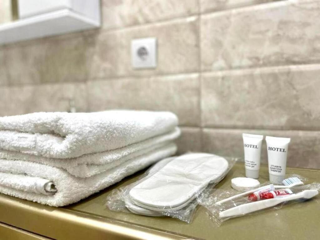 eine Badezimmertheke mit Handtüchern und anderen Gegenständen darauf in der Unterkunft Кабанбай батыра 58б/7 in Astana
