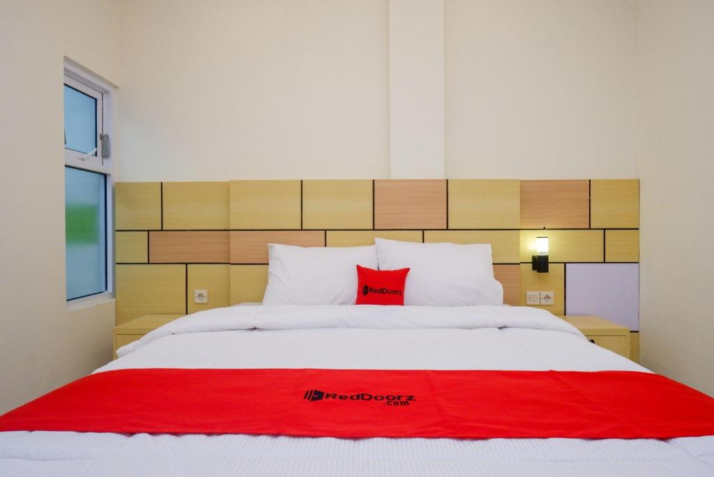 a large white bed with a red blanket on it at RedDoorz Plus near Pasar Gede Solo in Solo