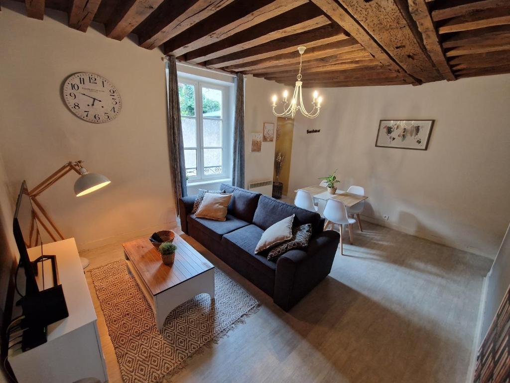 sala de estar con sofá y reloj en la pared en Le Saint Jean et son parking privée en Blois