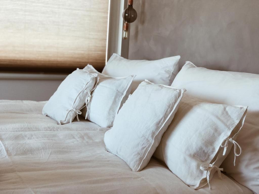 ein weißes Bett mit vier Kissen darauf in der Unterkunft AVLiving City INSIDE NINE Basel in Basel