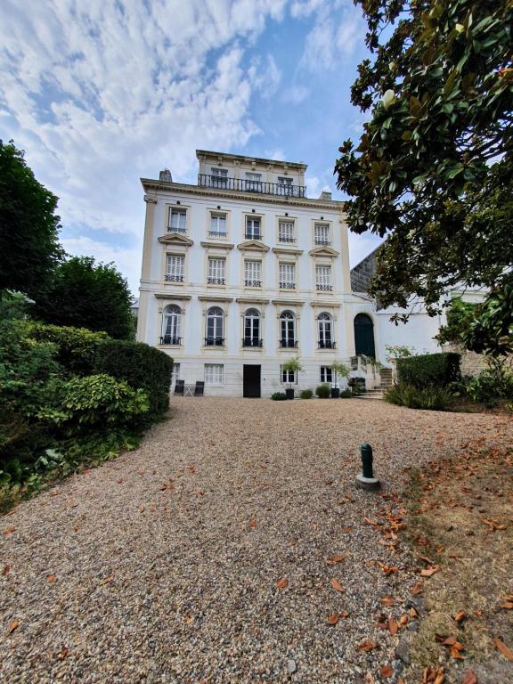 un grand bâtiment blanc sur une route en gravier dans l'établissement LA PARENTHÈSE HAVRAISE - Parking privé Plein centre & Très calme, au Havre