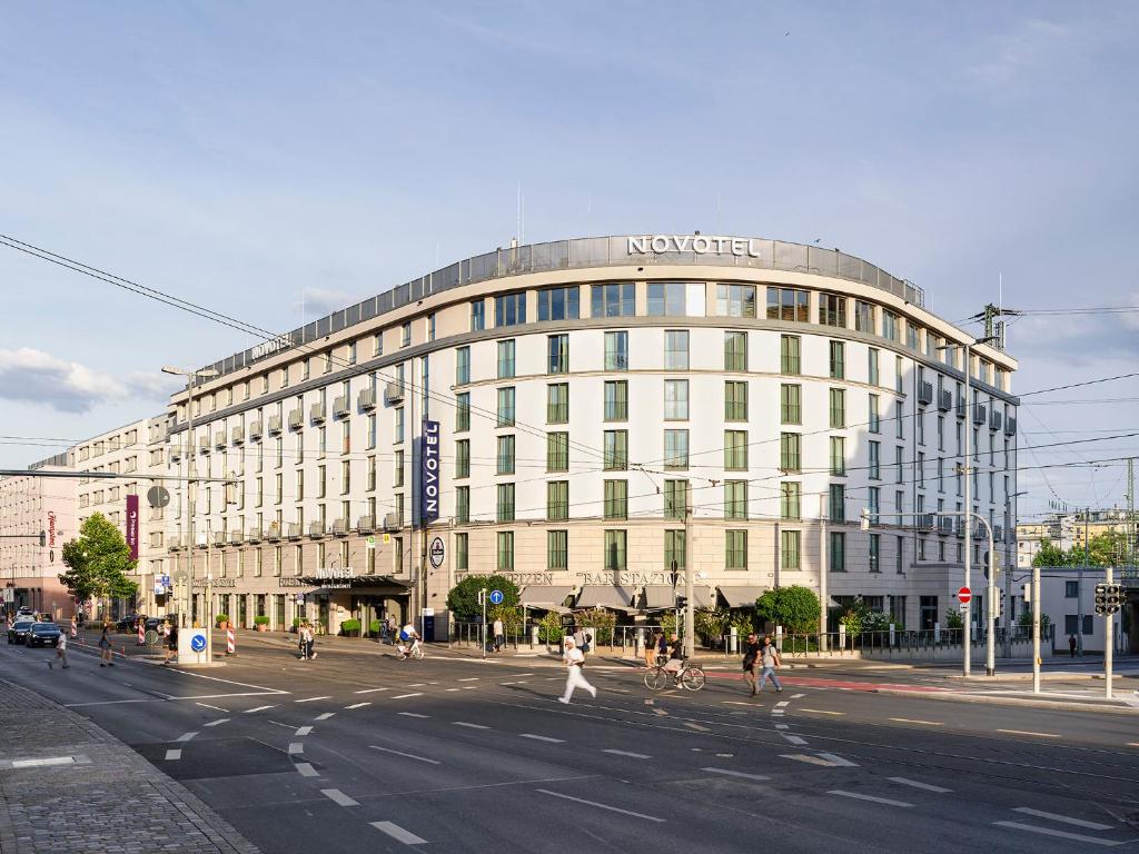 un gran edificio en una calle de la ciudad con gente cruzando la calle en Novotel Nuernberg Centre Ville en Núremberg