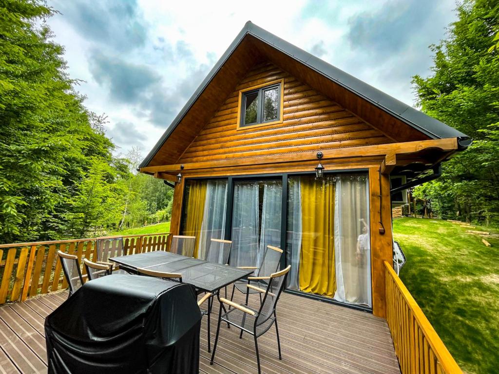 a cabin with a table and chairs on a deck at Leśne Zacisze Iwkowa in Iwkowa