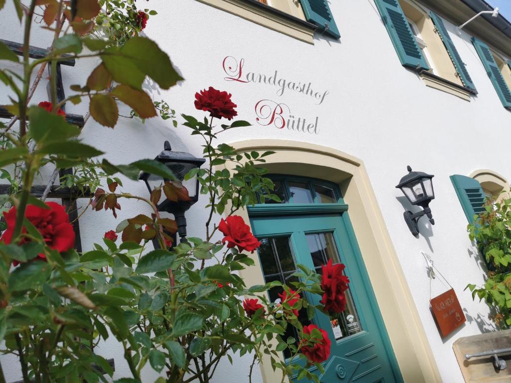 ein Gebäude mit grüner Tür und roten Blumen in der Unterkunft Landgasthof Büttel in Geisfeld