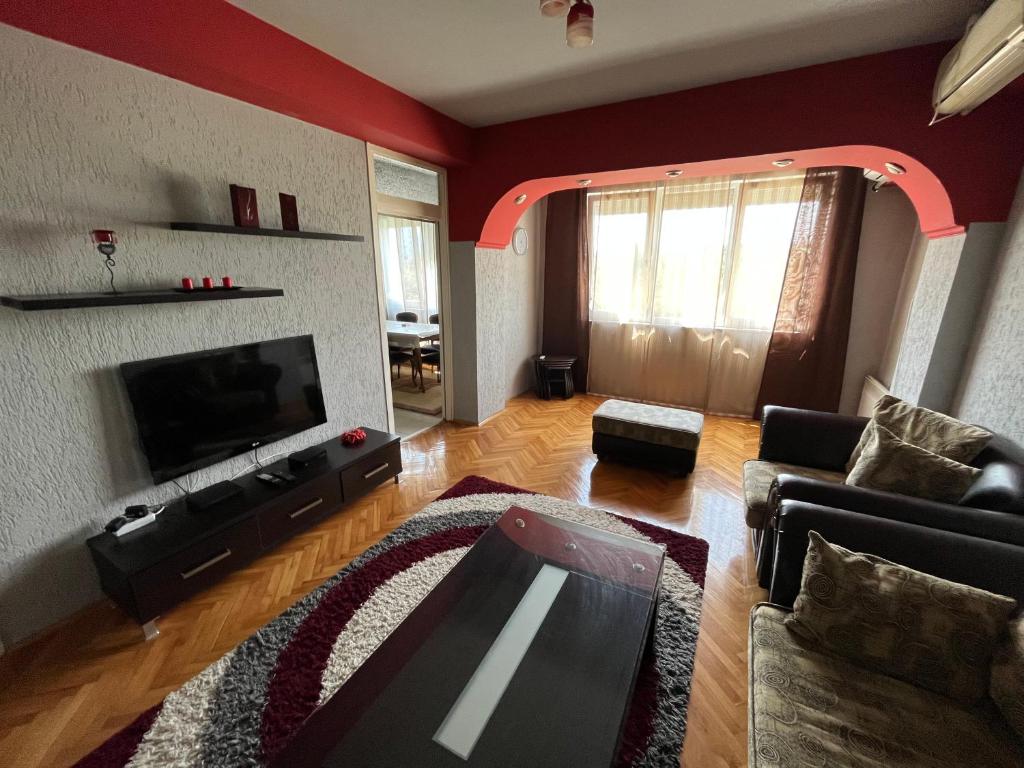 een woonkamer met een bank en een flatscreen-tv bij Mickitos MM Apartment in Skopje