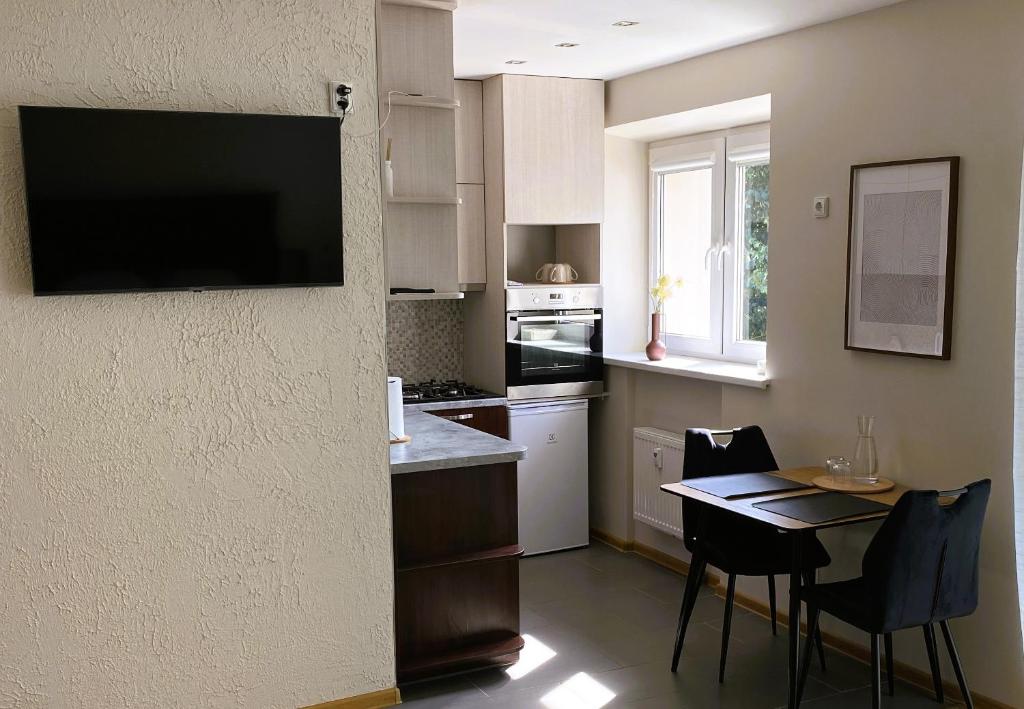 a kitchen with a table and a television on the wall at S&A apartamentai in Panevėžys