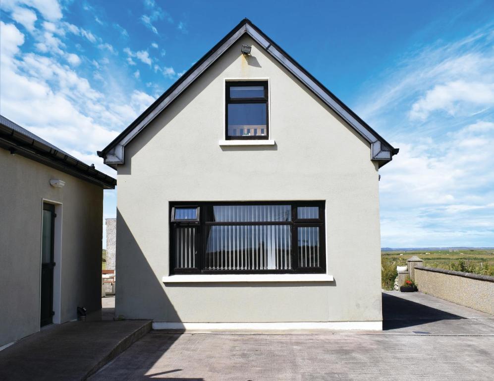 a white house with a window on top of it at Cosy two bedroom cottage on the Mullet Peninsula in Ballina