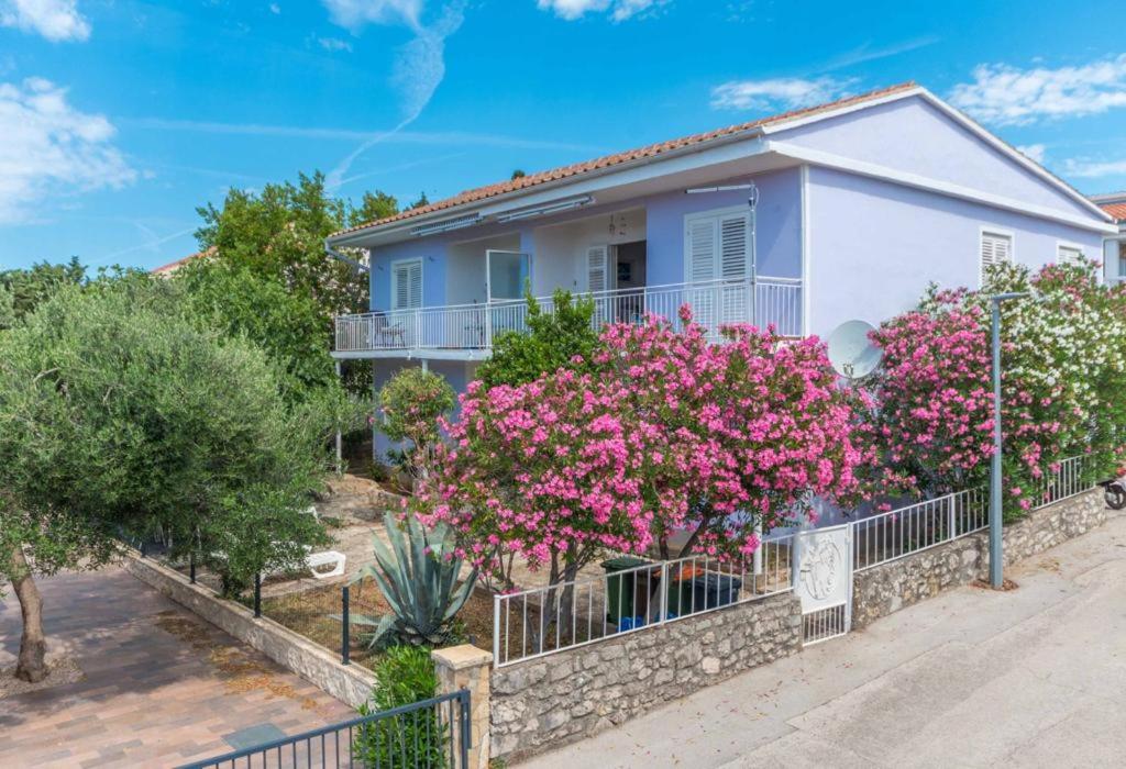 a house with pink flowers in front of a fence at Neptun apartments in Pirovac