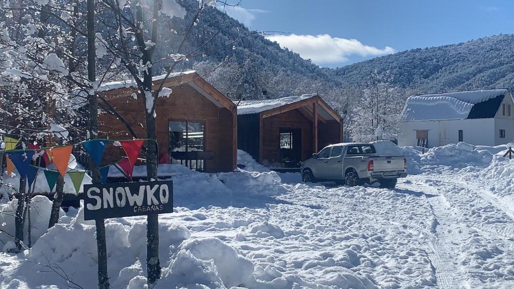 einen schneebedeckten Hof mit einem Haus und einem Auto in der Unterkunft Snowko in Malalcahuello