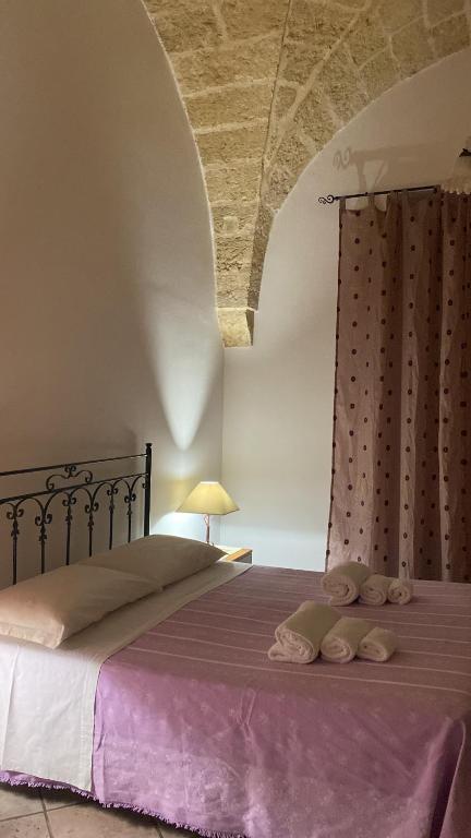 una camera da letto con un grande letto con una coperta viola di Casa Roma a Specchia