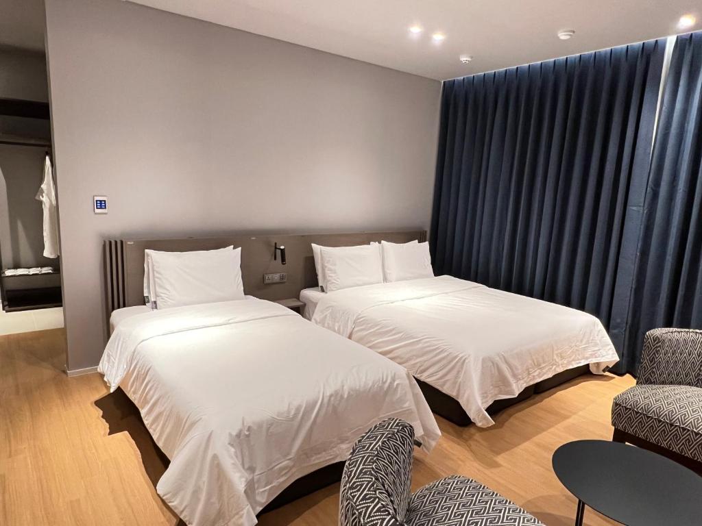 a bedroom with two beds and a chair and a couch at Jinhae Intercity Hotel in Changwon