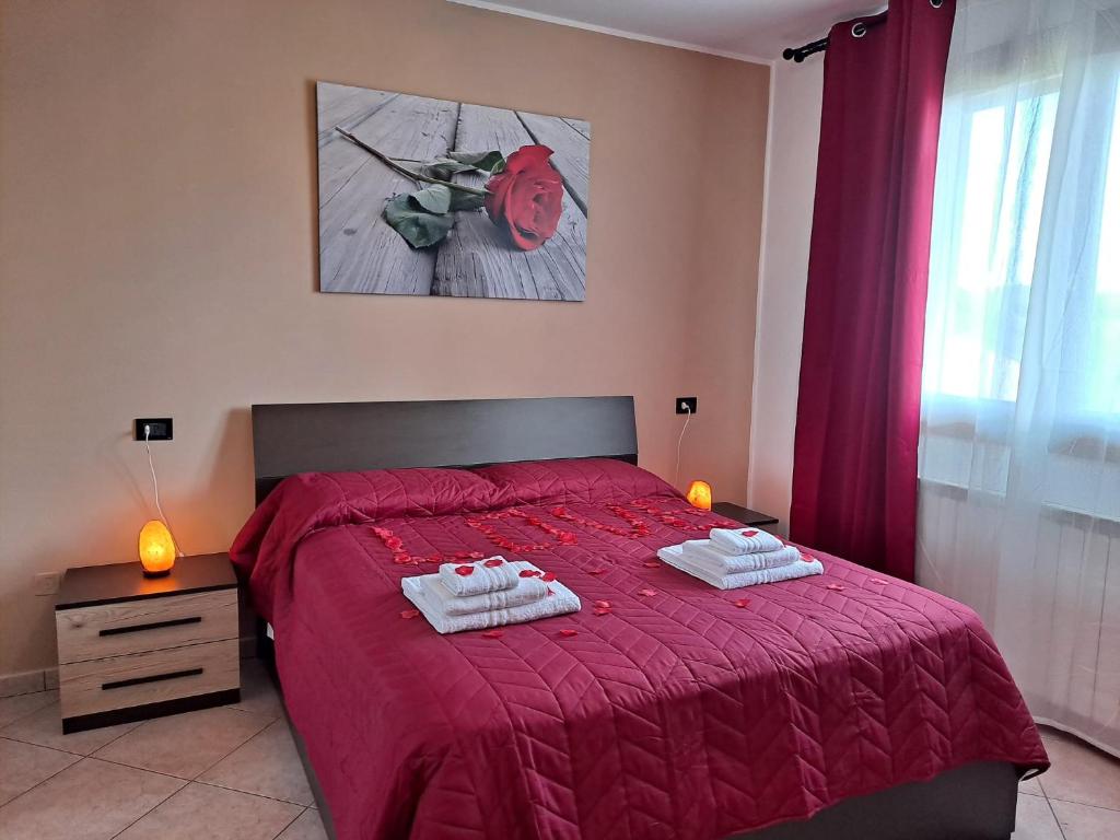 een slaapkamer met een rood bed en 2 handdoeken erop bij Appartamento Roverella in Rovigo