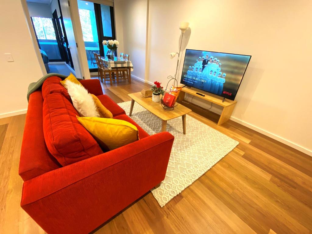a living room with a red couch and a television at New 2 Bed 2 Bath Apt at The Heart of Canberra - 2 Car Spaces in Canberra