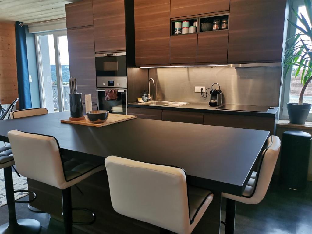 eine Küche mit einem Tisch und Stühlen im Zimmer in der Unterkunft Superbe appartement neuf avec terrasse in Orchamps-Vennes
