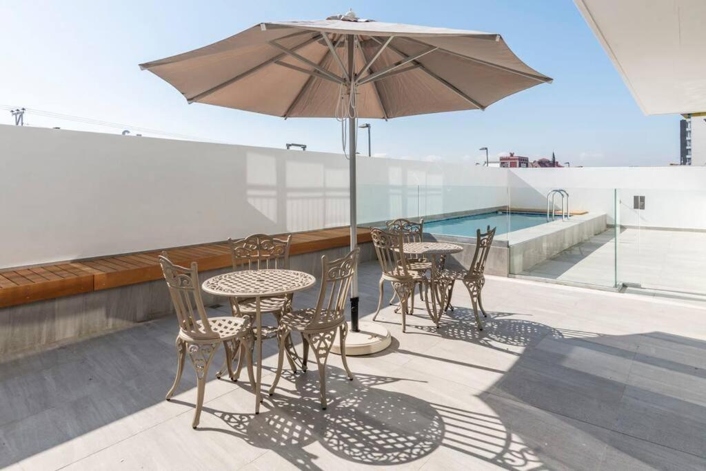 eine Terrasse mit Tischen, Stühlen und einem Sonnenschirm in der Unterkunft Contemporary arty Studio Balcony Mountain views in Kapstadt