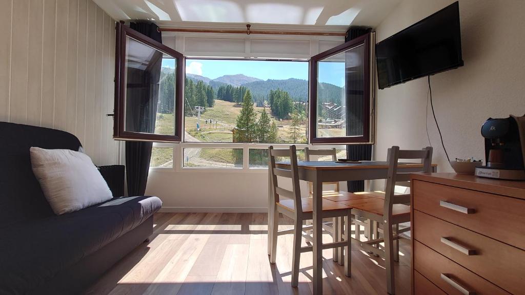 a room with a table and chairs and a large window at Le Portillo in Puy-Saint-Vincent
