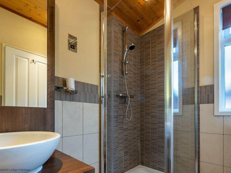 a bathroom with a shower with a sink and a tub at Windermere Retreat - White Cross Bay Holiday Park in Windermere