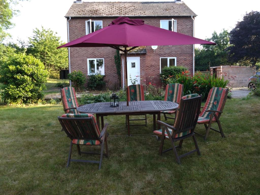 a table with chairs and an umbrella in a yard at Avryn - Delightful 3 bedroom cottage with stunning vistas in Mainstone