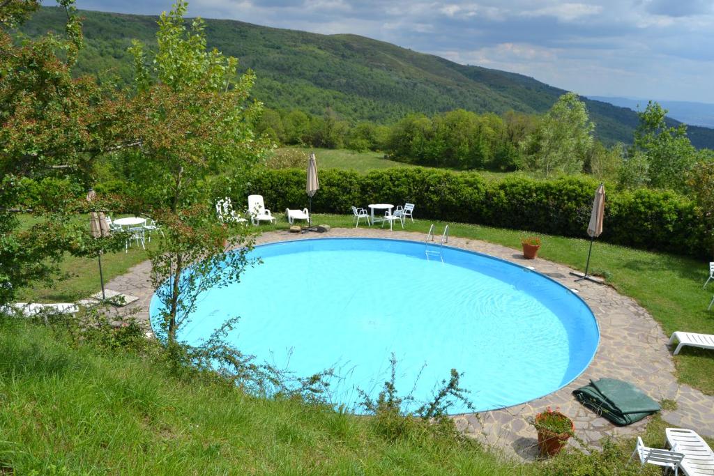 uma piscina num campo com cadeiras e mesas em Two-room apartment in Tuscan rustic style em La Lama