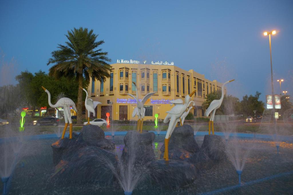 a fountain with white birds in front of a building at Al Massa Plus Hotel in Al Ain