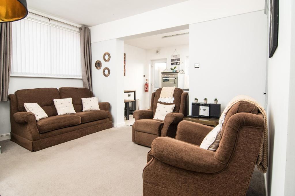 ein Wohnzimmer mit 2 Stühlen und einem Sofa in der Unterkunft ALTIDO Family house with courtyard in Hoylake in Hoylake