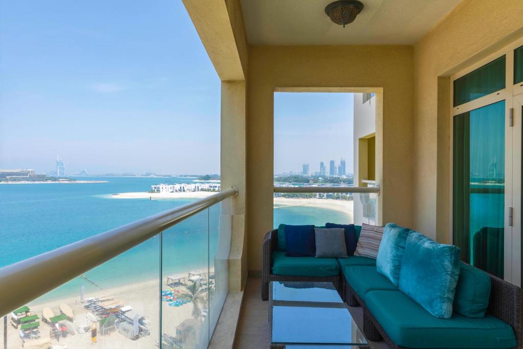 a balcony with a couch and a view of the ocean at Maison Privee - Beach Access Apt with Burj & Sea Views on The Palm in Dubai