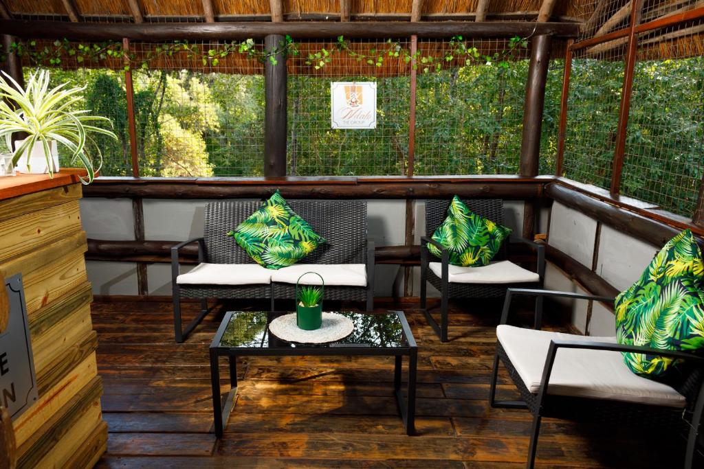eine Veranda mit Stühlen und einem Tisch mit einem Getränk darauf in der Unterkunft Ndalo Lodge Mbombela in Nelspruit