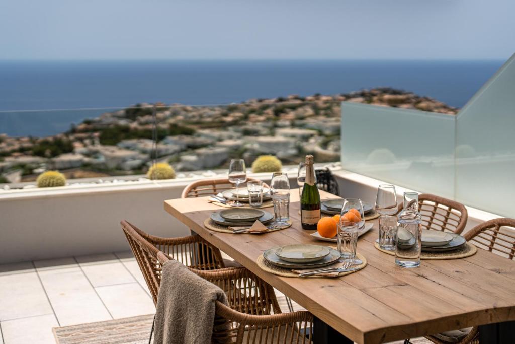 drewniany stół z kieliszkami do wina i pomarańczami na balkonie w obiekcie Infinity Horizon Apartment - Costa Blanca w mieście Cumbre del Sol