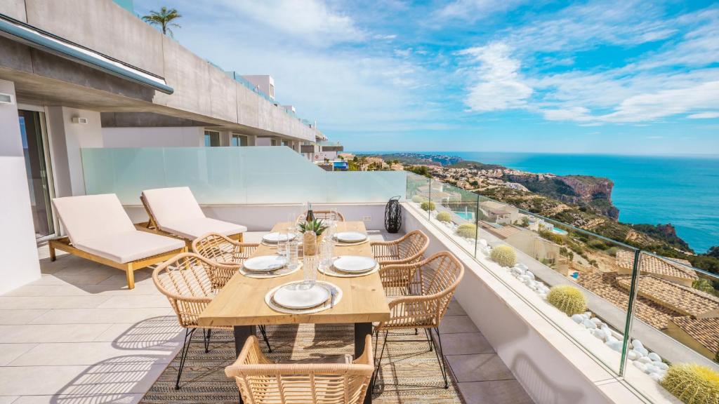 balkon ze stołem i krzesłami oraz oceanem w obiekcie Infinity Horizon Apartment - Costa Blanca w mieście Cumbre del Sol