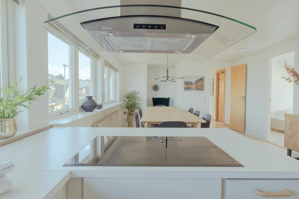 a kitchen with white counters and a dining room with a table at 5 BR Penthouse Apartment / Downtown / Marina in Tórshavn