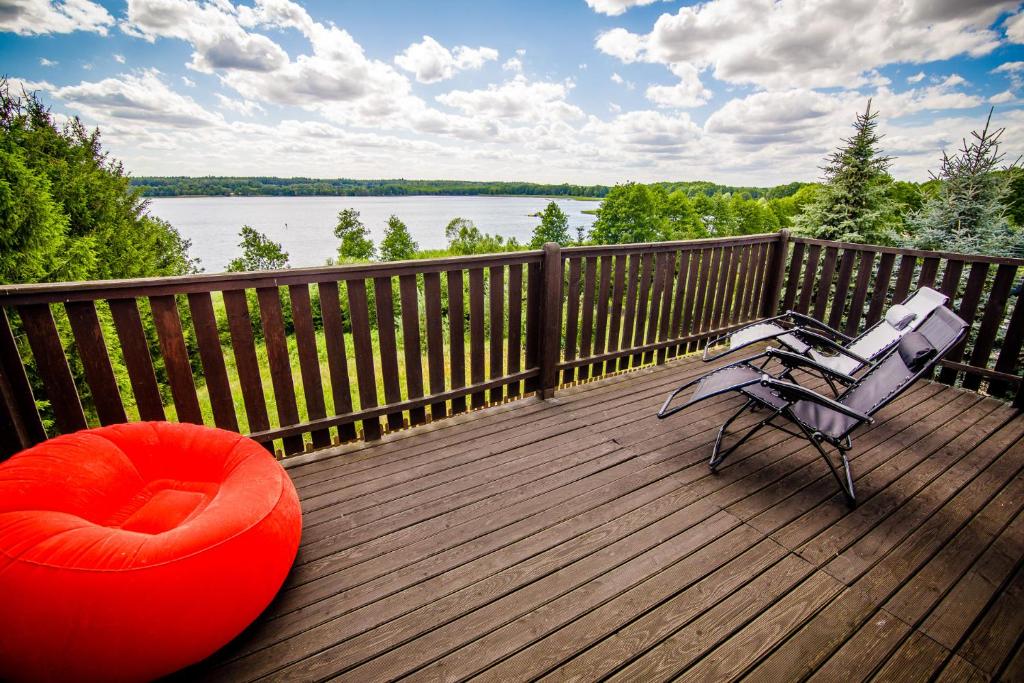 a wooden deck with a bench and a red ottoman at Domek na skarpie in Rybno