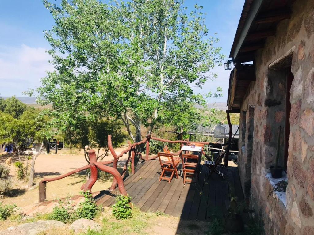 una terrazza in legno con tavolo e sedie su una casa di Pachamama cabañas en la montaña a Mina Clavero