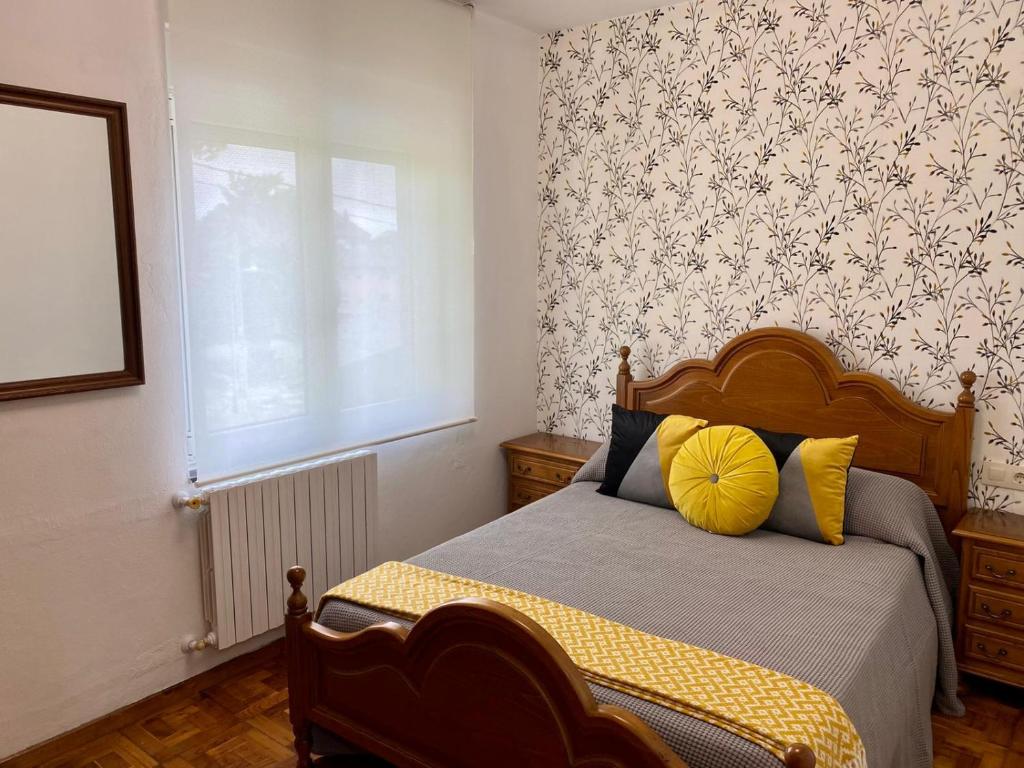 a bedroom with a bed with yellow pillows and a window at La Quintana in La Espina