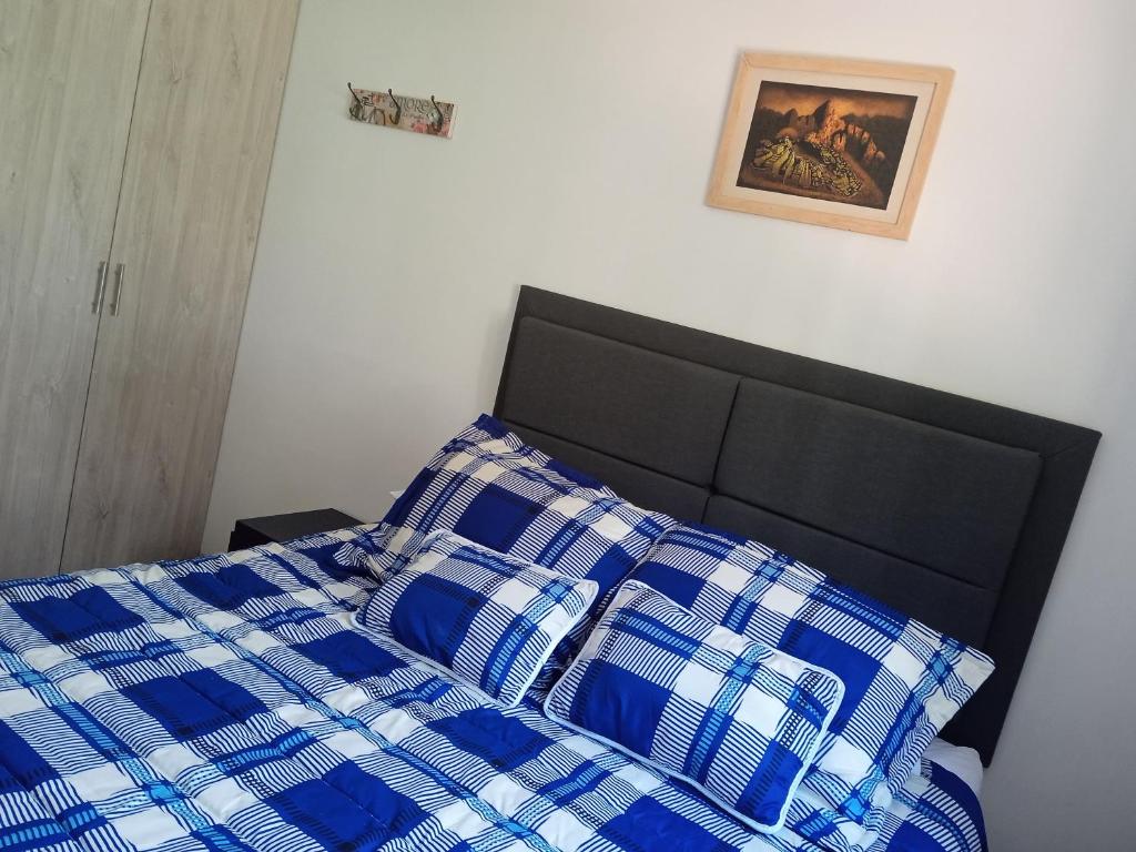 a bed with a blue and white checkered blanket at Apartamento Quintas de San Javier in Medellín