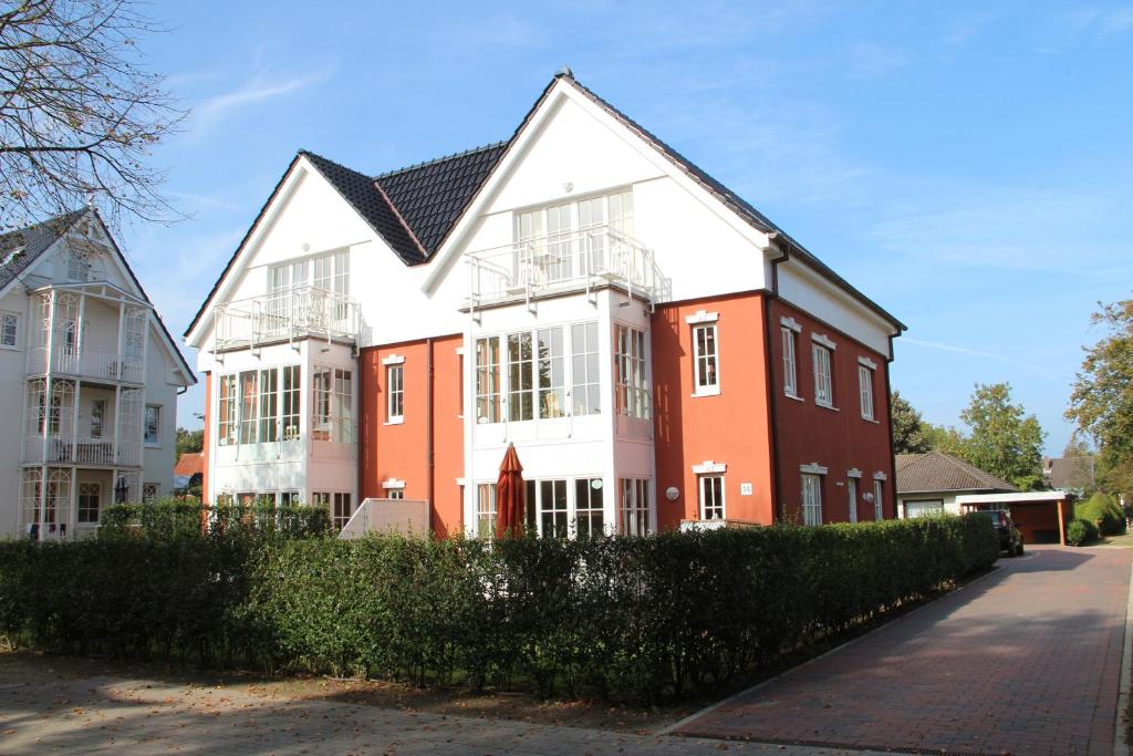 a large white and orange house on a street at Ferienwohnung Seeschwalbe in Südstrand
