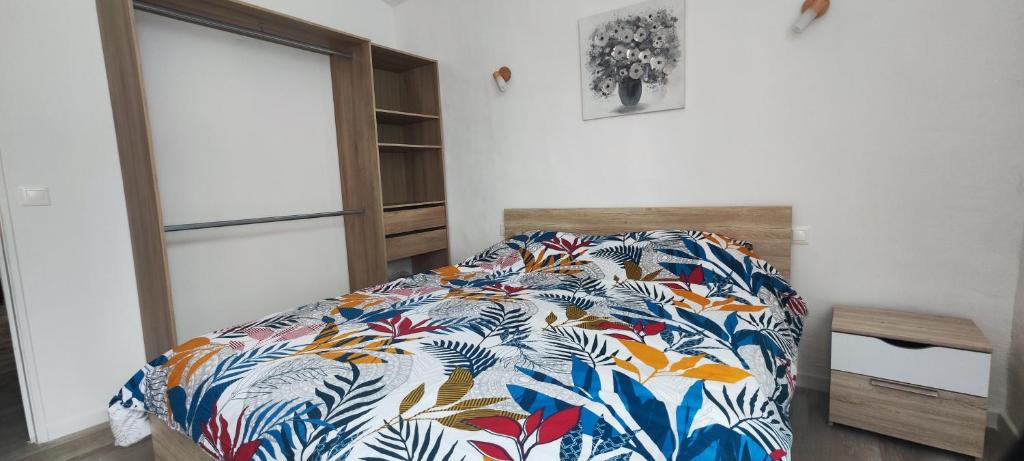 1 dormitorio con 1 cama con un edredón colorido en Appartement Le république idéalement situé., en Saint-Ambroix