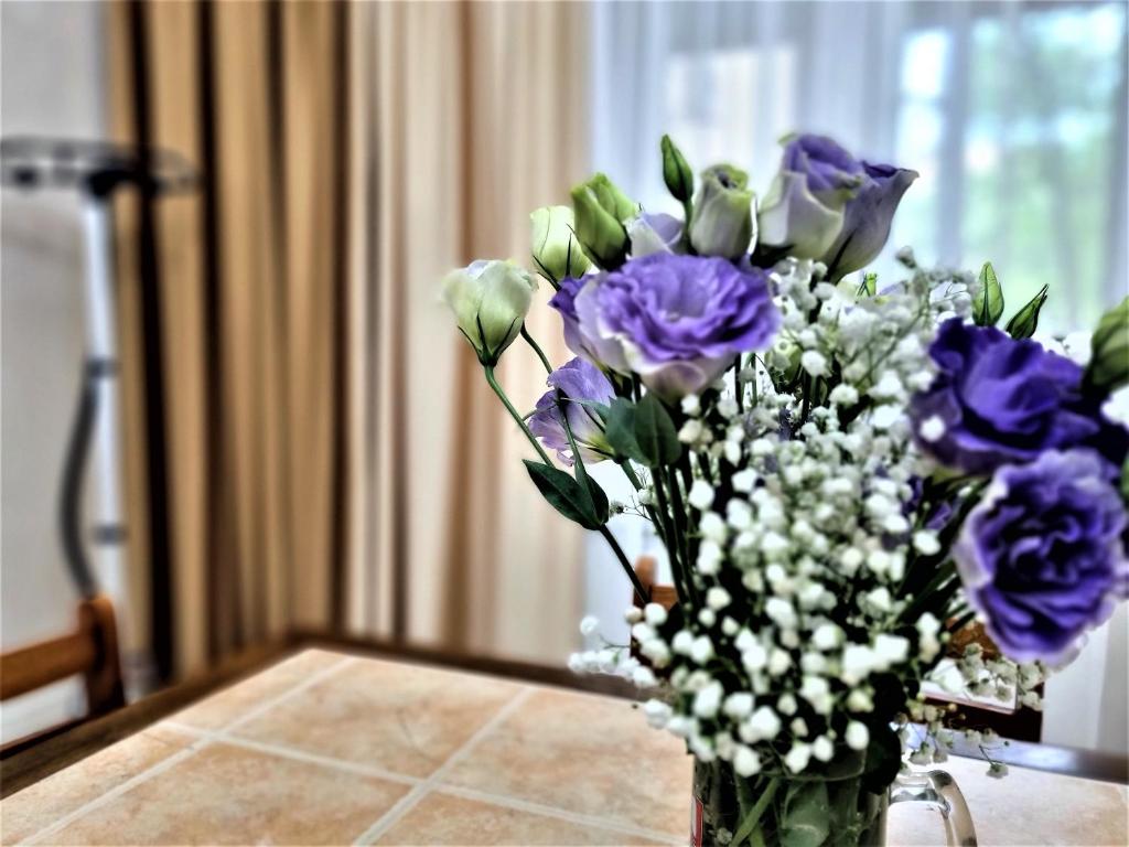a vase filled with purple flowers on a table at Очень уютная квартира рядом с посольством США in Almaty