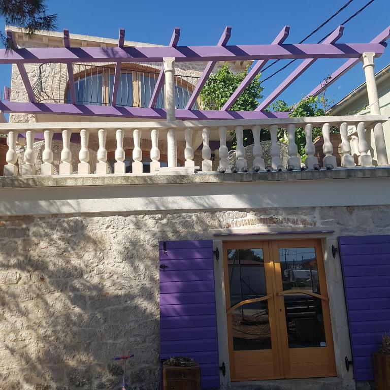 a purple house with a white railing and a door at jardin kapetanova kuća in Veli Iž