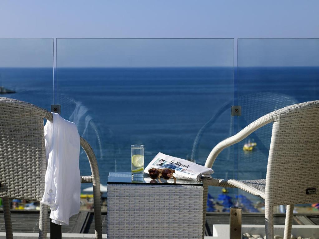 a table with a book and two chairs and a window at Kriti Beach Hotel in Rethymno