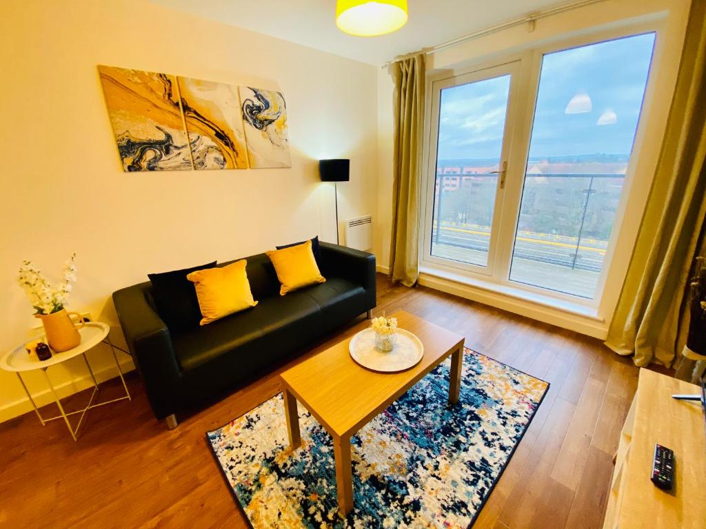 a living room with a black couch and a large window at Cloud9SA at The Nankeville Woking in Woking