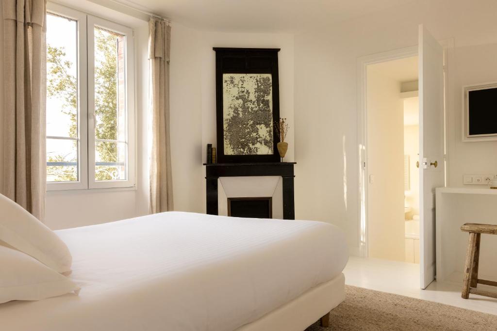 a white bedroom with a bed and a fireplace at Ô PLUM'ART Chambres de caractère in Giverny