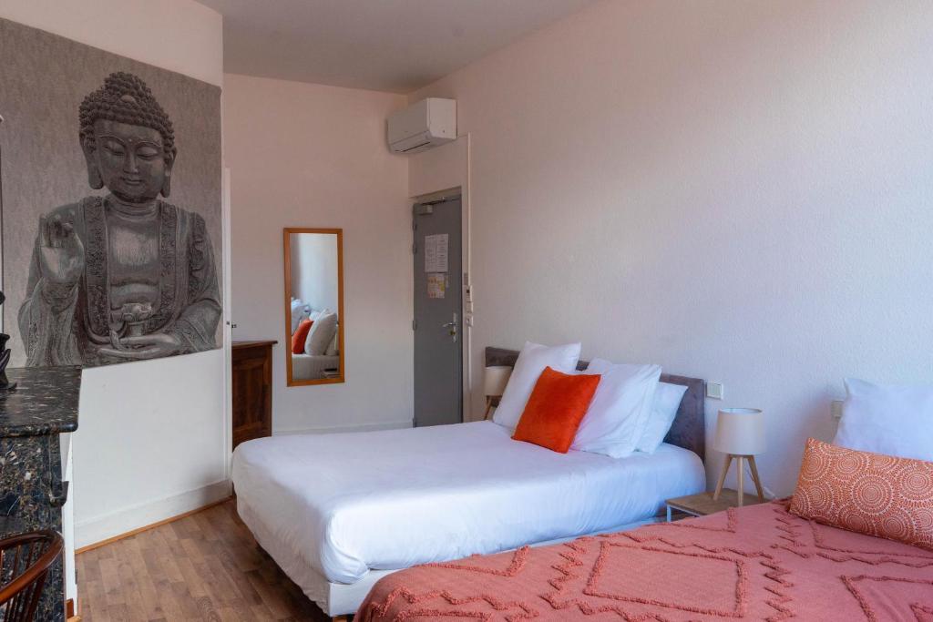 a bedroom with two beds and a statue on the wall at Hôtel Croix Baragnon in Toulouse