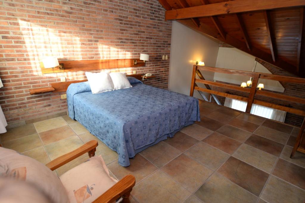 1 dormitorio con cama y pared de ladrillo en Aitue Apart Hotel & Spa en Valeria del Mar