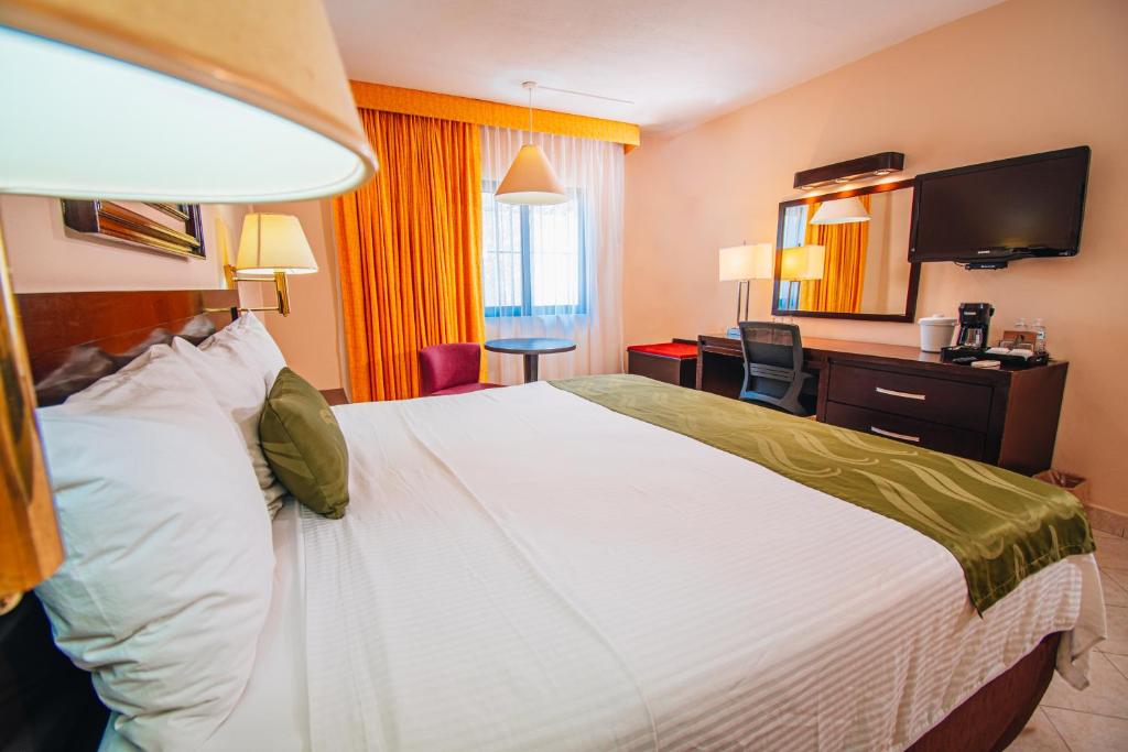 a hotel room with a large bed and a desk at Eco City Hoteles in Tuxtla Gutiérrez