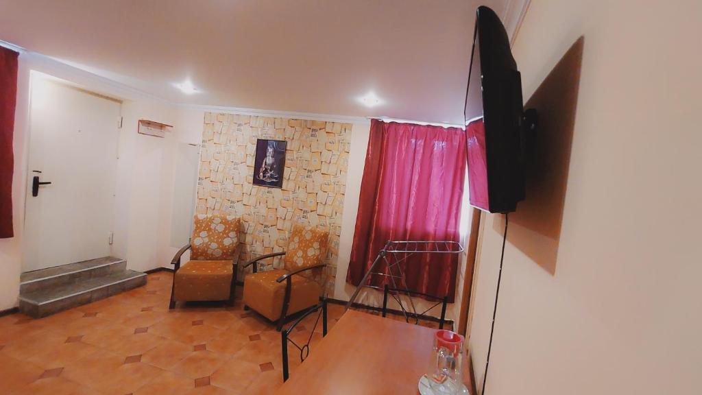 a living room with a tv and a red curtain at Buddha apartment in Tbilisi City