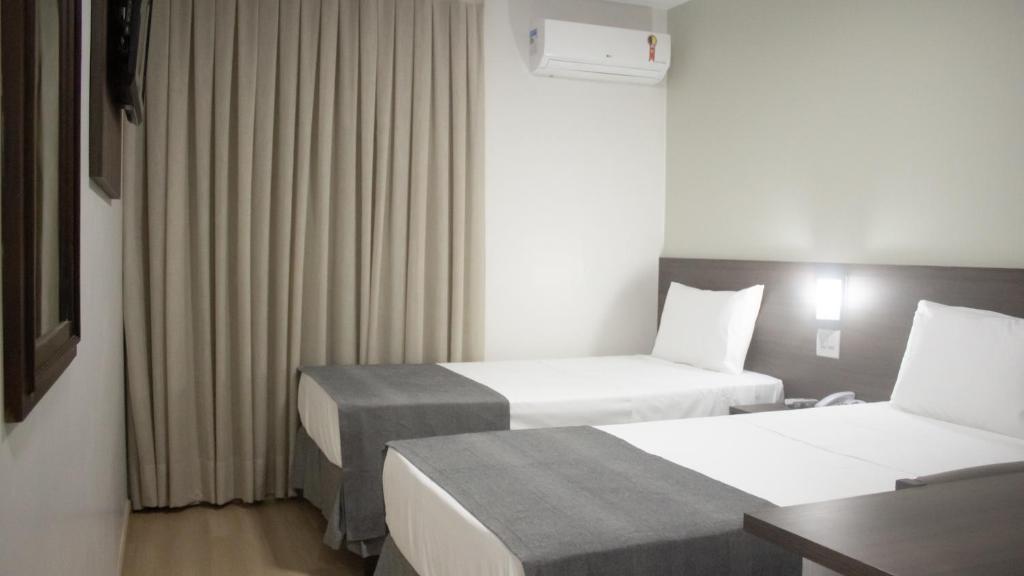 A bed or beds in a room at Essência Hotel Francisco Beltrão