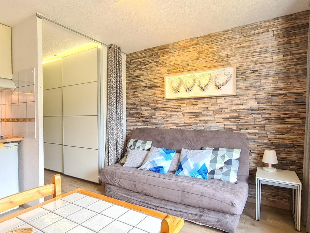 ein Wohnzimmer mit Sofa und Ziegelwand in der Unterkunft Studio Flaine, 1 pièce, 4 personnes - FR-1-425-154 in Flaine